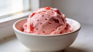 First scoop of no-churn strawberry ice cream made with fresh strawberries, sweetened condensed milk, and whipped cream
