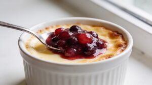 Baked vanilla custard with summer berry compote served in a ceramic dish