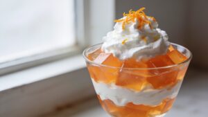 Layered creamsicle parfaits in glasses with orange gelatin and whipped cream