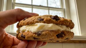 Homemade ice cream sandwiches with chocolate chip cookies and vanilla ice cream, stacked on a wooden board