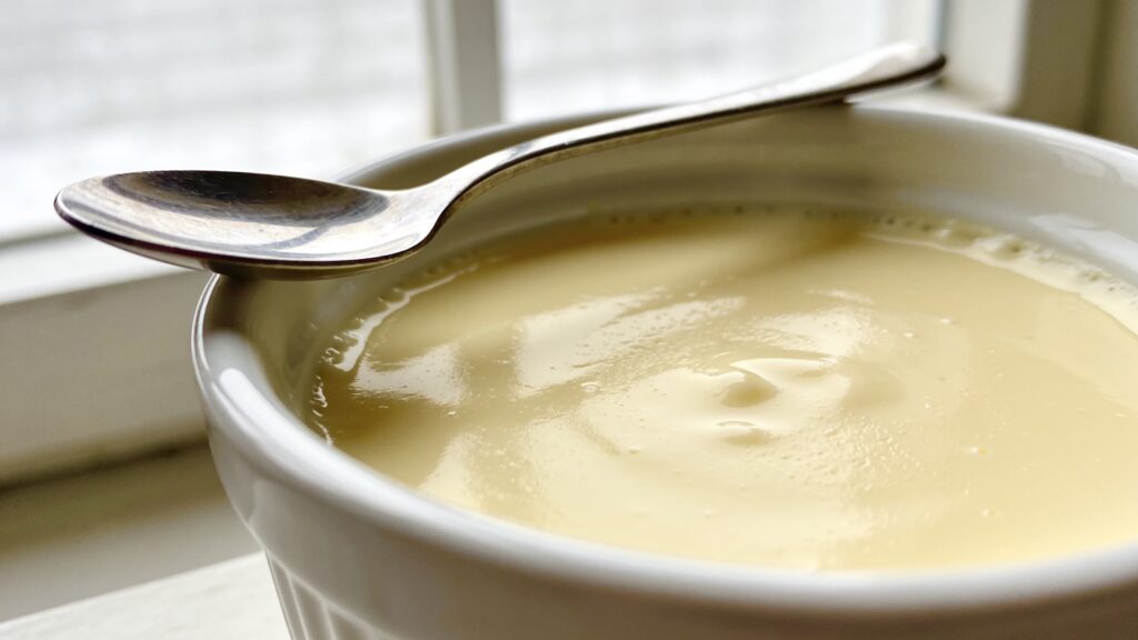 Creamy stovetop vanilla custard in a small bowl with a spoon, highlighting its smooth texture