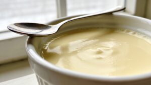 Creamy stovetop vanilla custard in a small bowl with a spoon, highlighting its smooth texture