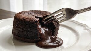 Molten chocolate lava cake served on a plate with a scoop of vanilla ice cream and a drizzle of chocolate sauce