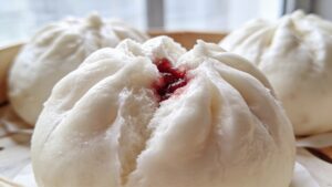 Fluffy steamed char siu bao buns on a bamboo steamer