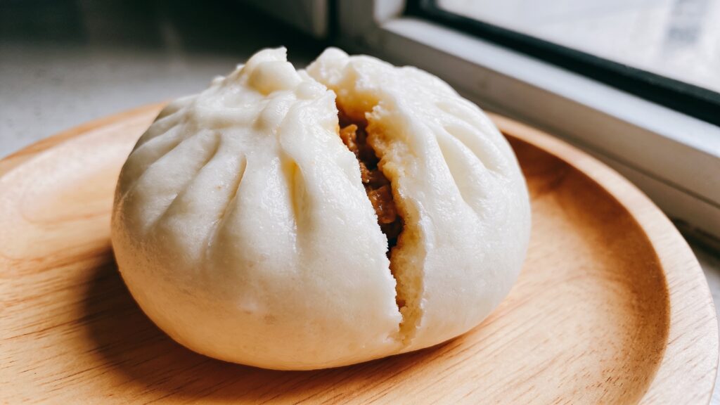 Fluffy steamed bao buns filled with spiced mushrooms, edamame, and pickled cucumber on a bamboo steamer
