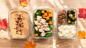 Keto meal prep containers with fall produce, eggs, and vegetables on a wooden table
