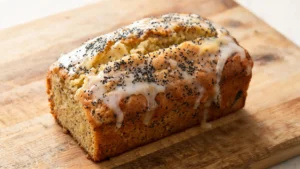 Moist vegan lemon poppy seed loaf on a wooden board with a slice cut out