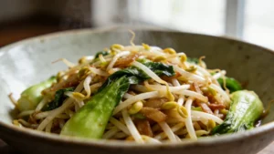 A bowl of veggie chop suey with bean sprouts, bok choy, and snap peas