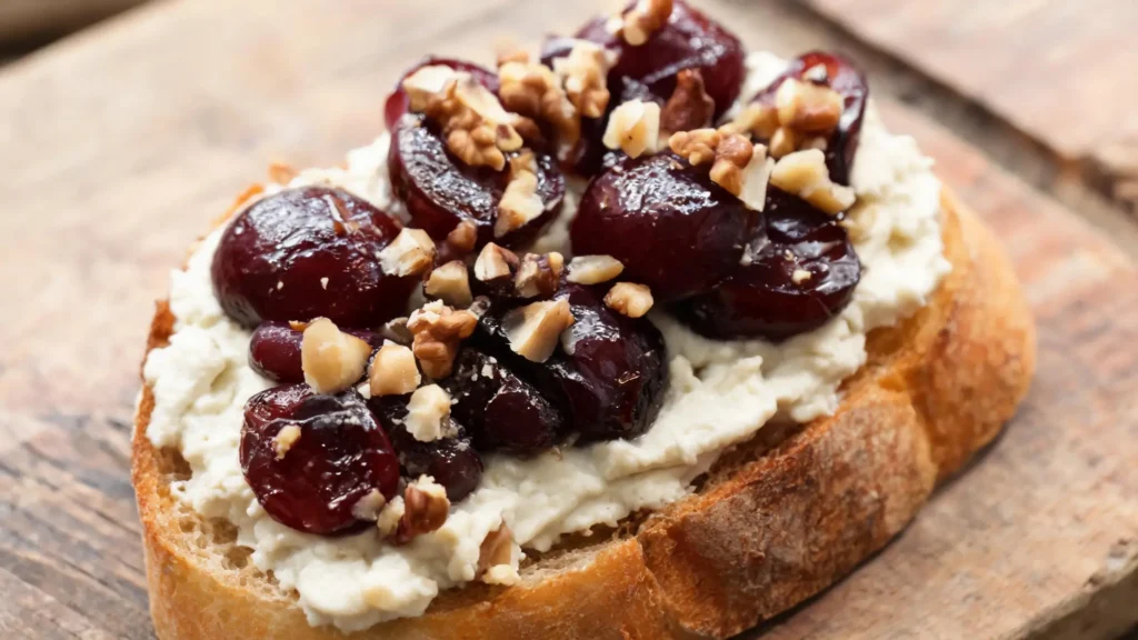 Vegan roasted grape and walnut crostini with dairy-free ricotta and fresh thyme on a wooden board