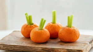 Tangerine pumpkins with celery stems on a plate