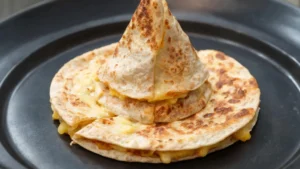 Witch hat black bean quesadillas on a plate with Halloween decorations