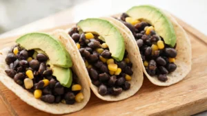 A plate of Black Bean and Corn Tacos with Avocado, topped with fresh salsa and cilantro