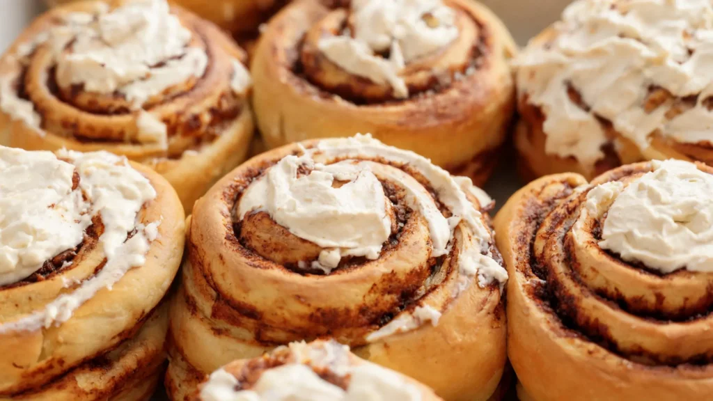 A plate of classic cinnamon buns topped with creamy cream cheese frosting