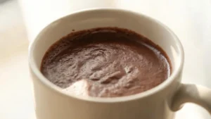 A steaming mug of rich classic hot cocoa made with dark cocoa powder and oat milk, topped with a dollop of foam