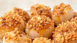 Crispy golden panko-crusted scallops drizzled with hot honey on a plate