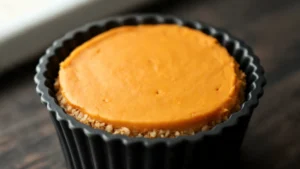 Two creamy keto pumpkin cheesecake cups with almond flour crust on a plate