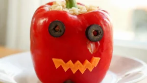 Two vegan stuffed bell pepper monsters with googly eyes and black bean filling on a plate