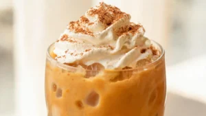 Pumpkin Spice Frappe in a glass with whipped cream and autumn leaves
