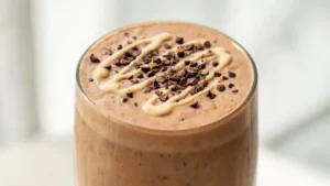 Tall glass of tahini date coffee frappe topped with sesame seeds and tahini drizzle