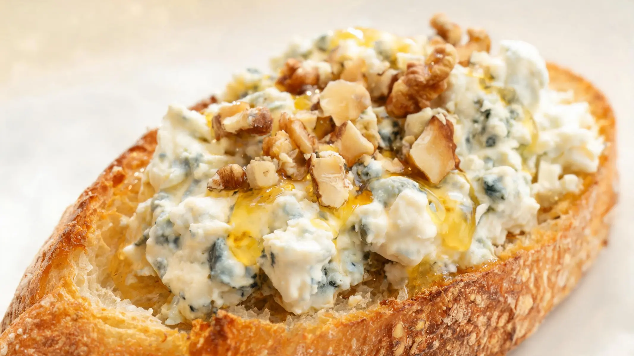 A platter of whipped blue cheese hot honey crostini, drizzled with hot honey and garnished with herbs.