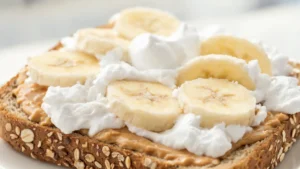Whole-grain fluffernutter toast topped with sliced banana on a plate