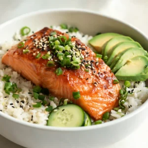 A colorful chili crisp salmon rice bowl topped with green onions, sesame seeds, and a glossy glaze